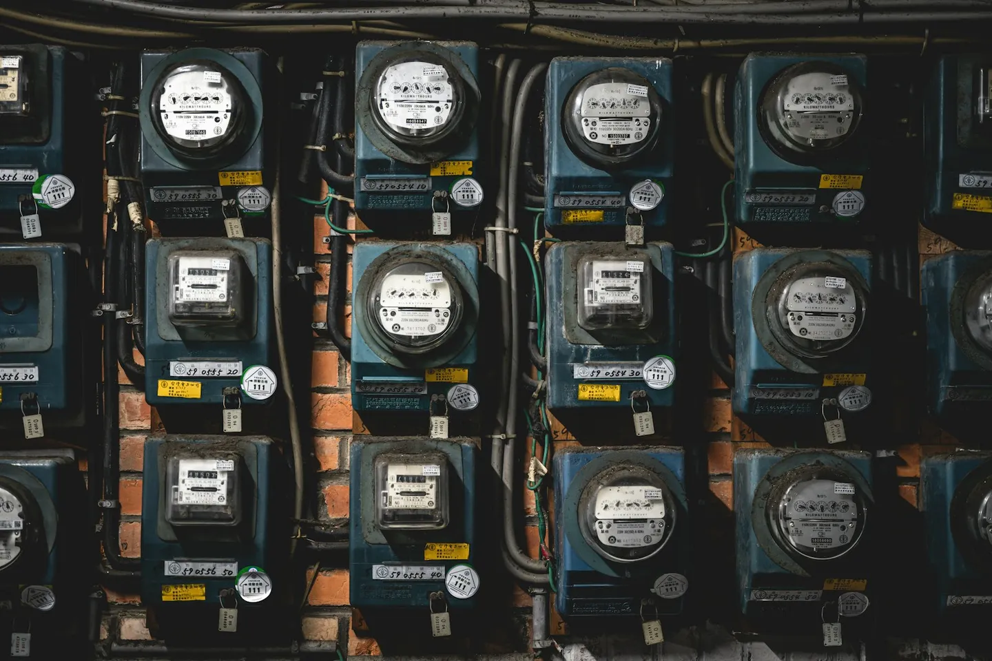 Rows of stacked electrical meters mounted on a wall, the kind of multi-tenant commercial metering bank feeding half-hourly consumption data
