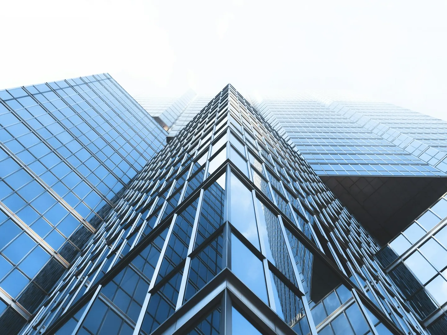 Low-angle view of glass curtain-wall commercial buildings against a clear sky