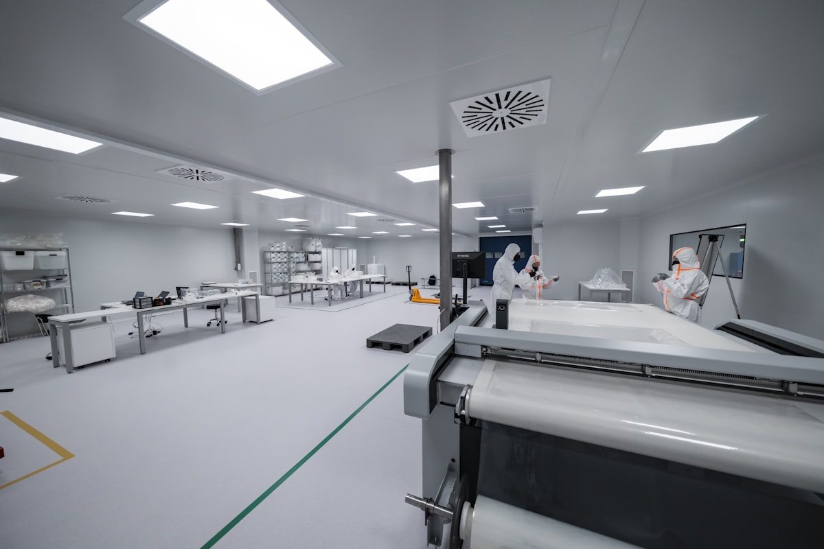 Arbeidere i et cleanroom-produksjonsmiljø med verneutstyr og synlig produksjonsmaskineri