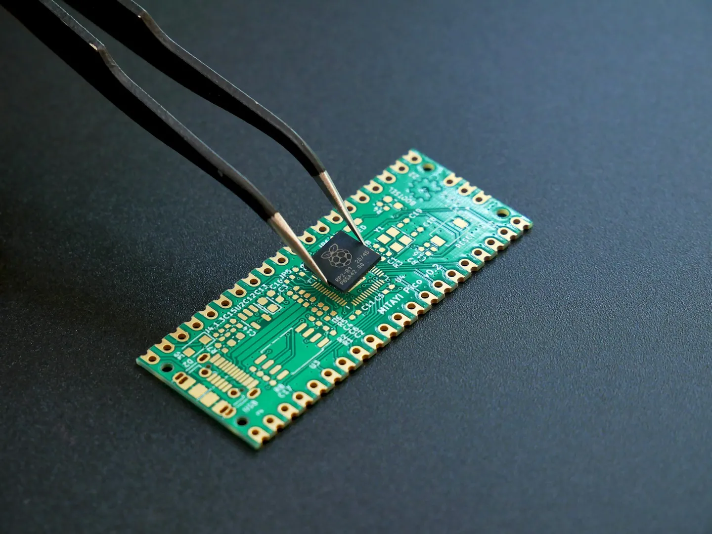 Pincet der placerer en lille mikrochip på et grønt printkort